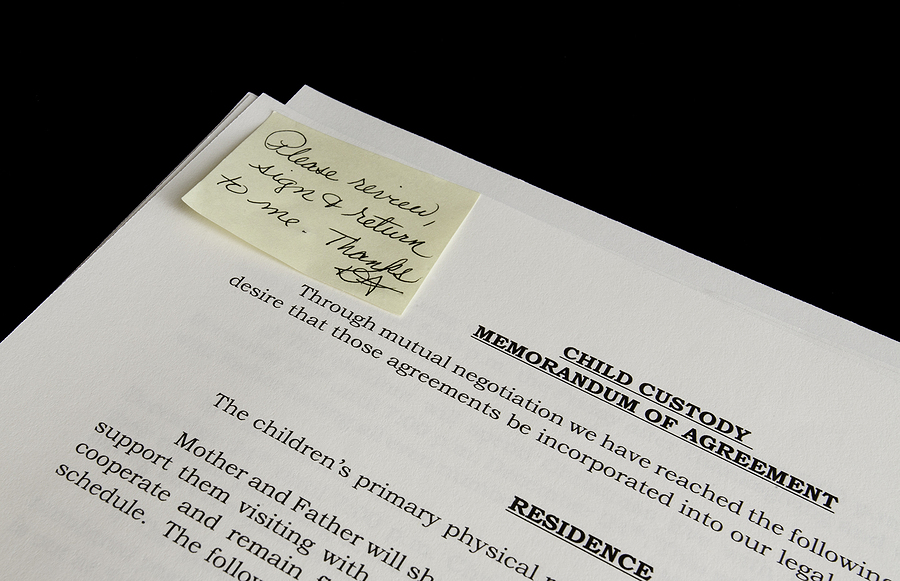 How a Child Custody Attorney for Fathers’ Rights Makes a Difference, Divorce or Child Custody papers laying on a black table ready to be reviewed, signed and returned.